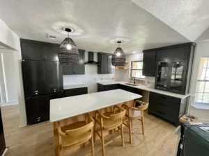 Kitchen with dark charcoal cabinets, a wood-base island, white quartz countertops, and woven pendant lights